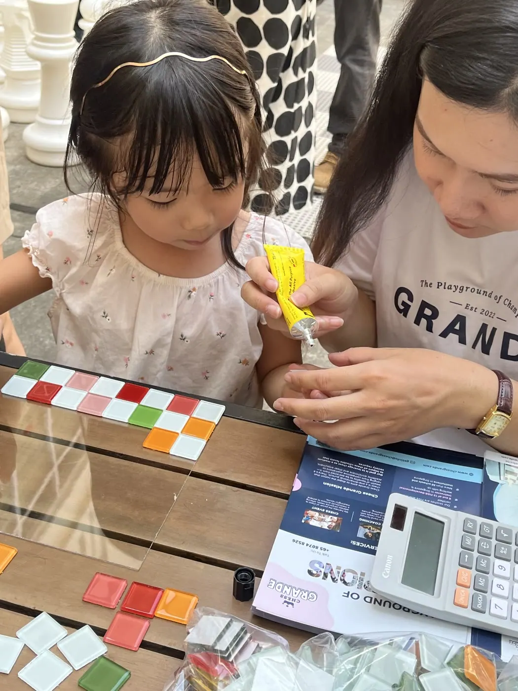 A Chess Grande volunteer helping a child assemble a chess piece