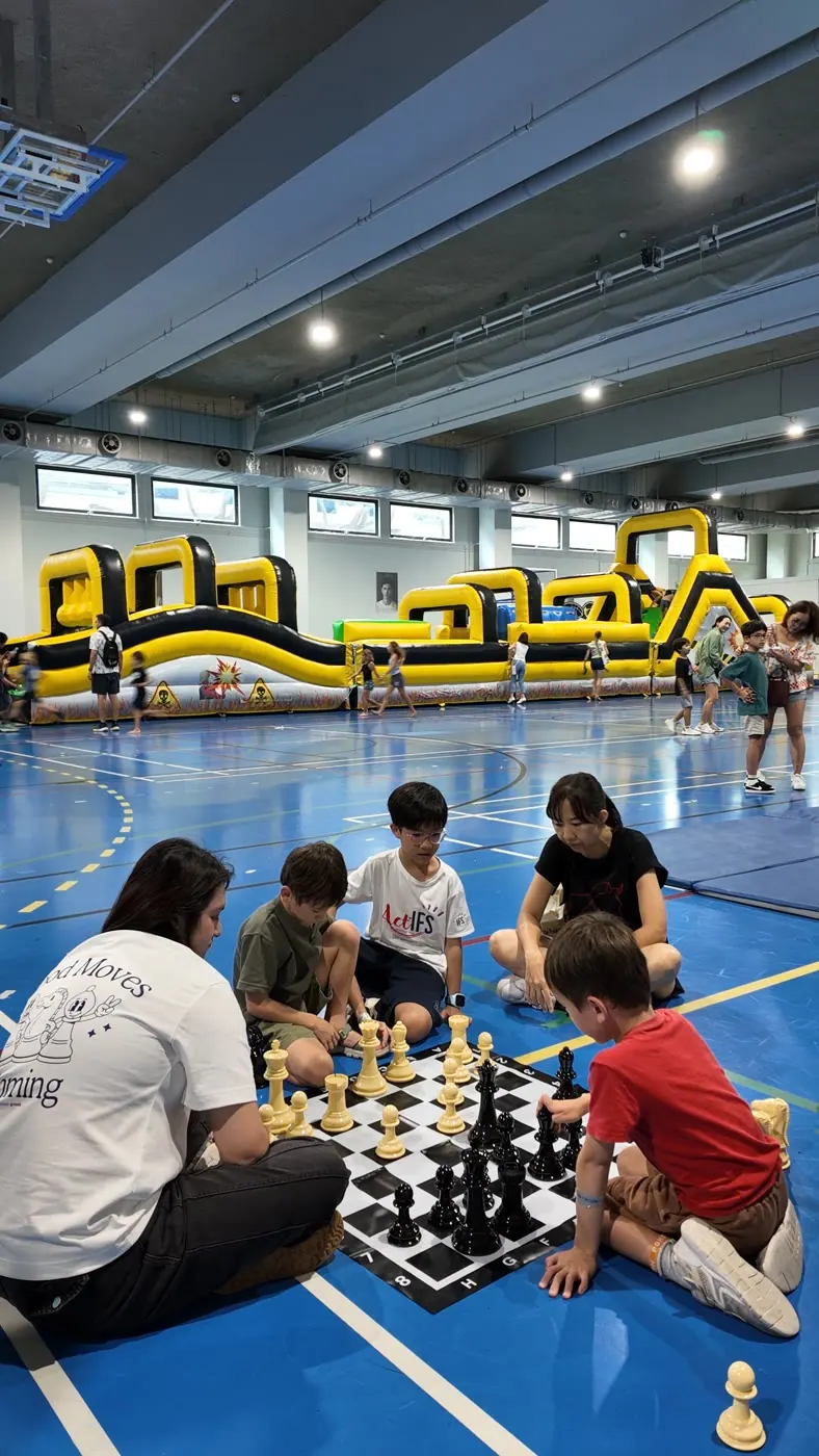 Children gathered around Chess Grande activity tables at Fête de l’École
