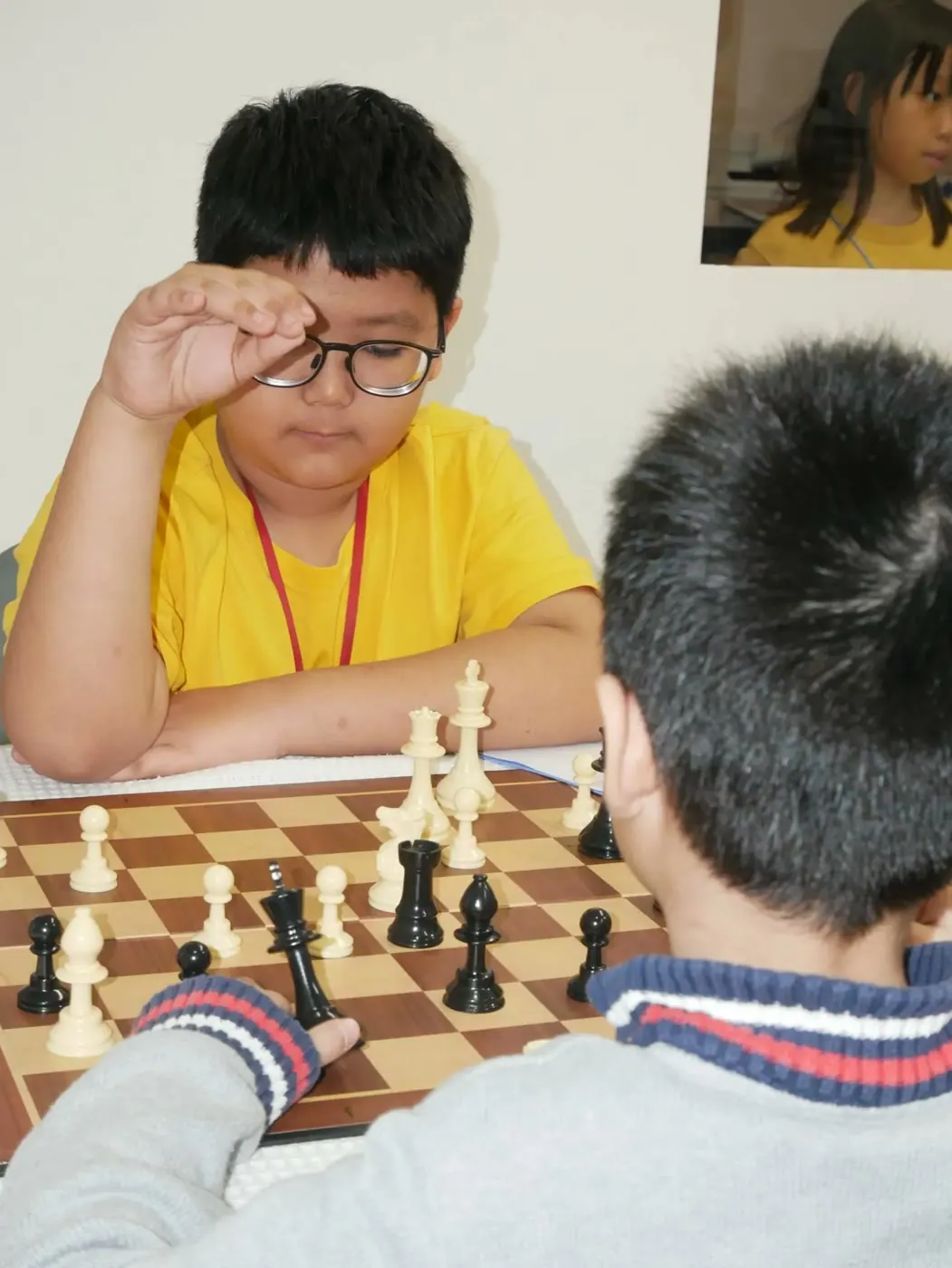 A player in a yellow shirt studying the chessboard