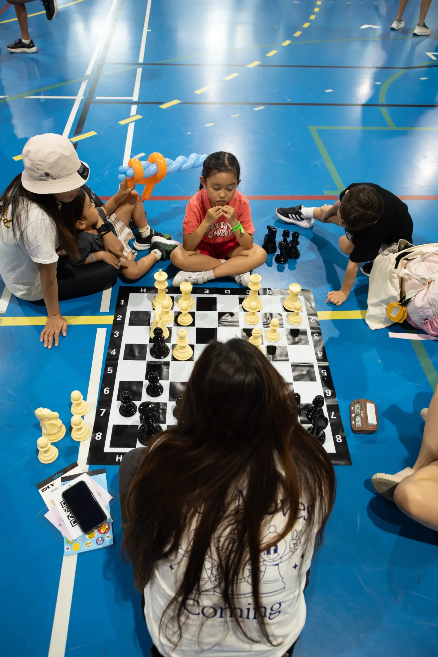Children playing on a giant floor chess set at Fête de l’École