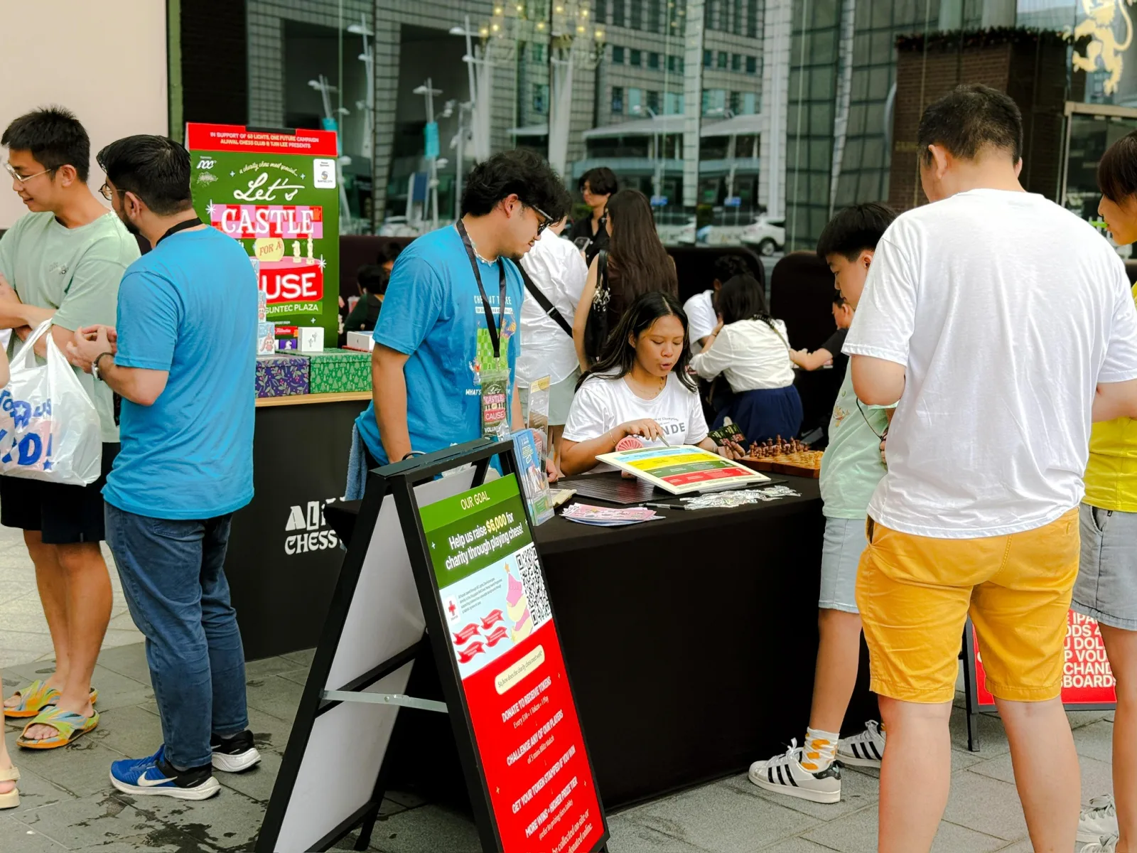 Visitors gathering around the Chess Grande table at a community event