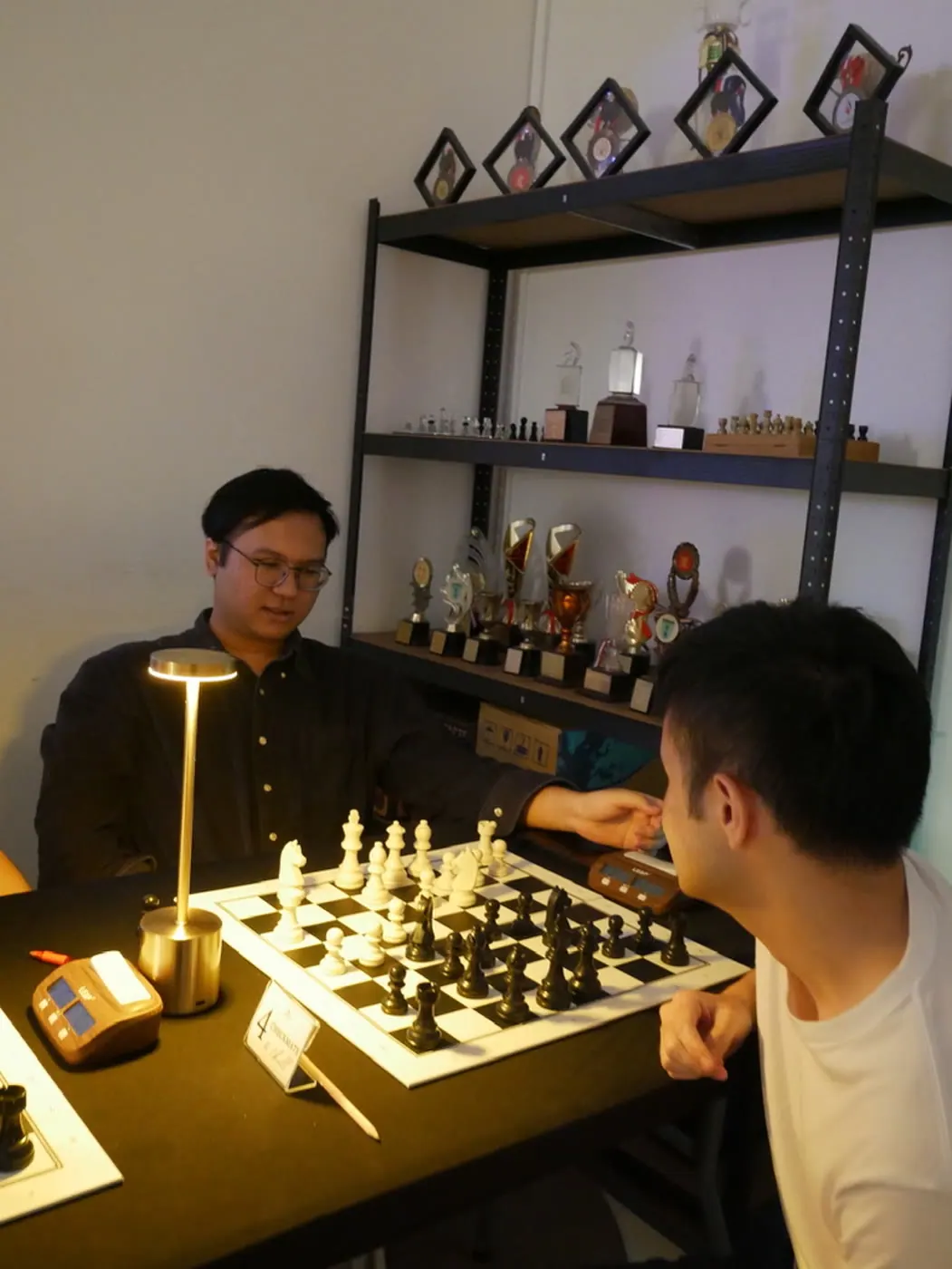 Two adults playing chess by lamplight at Checkmate and Chill