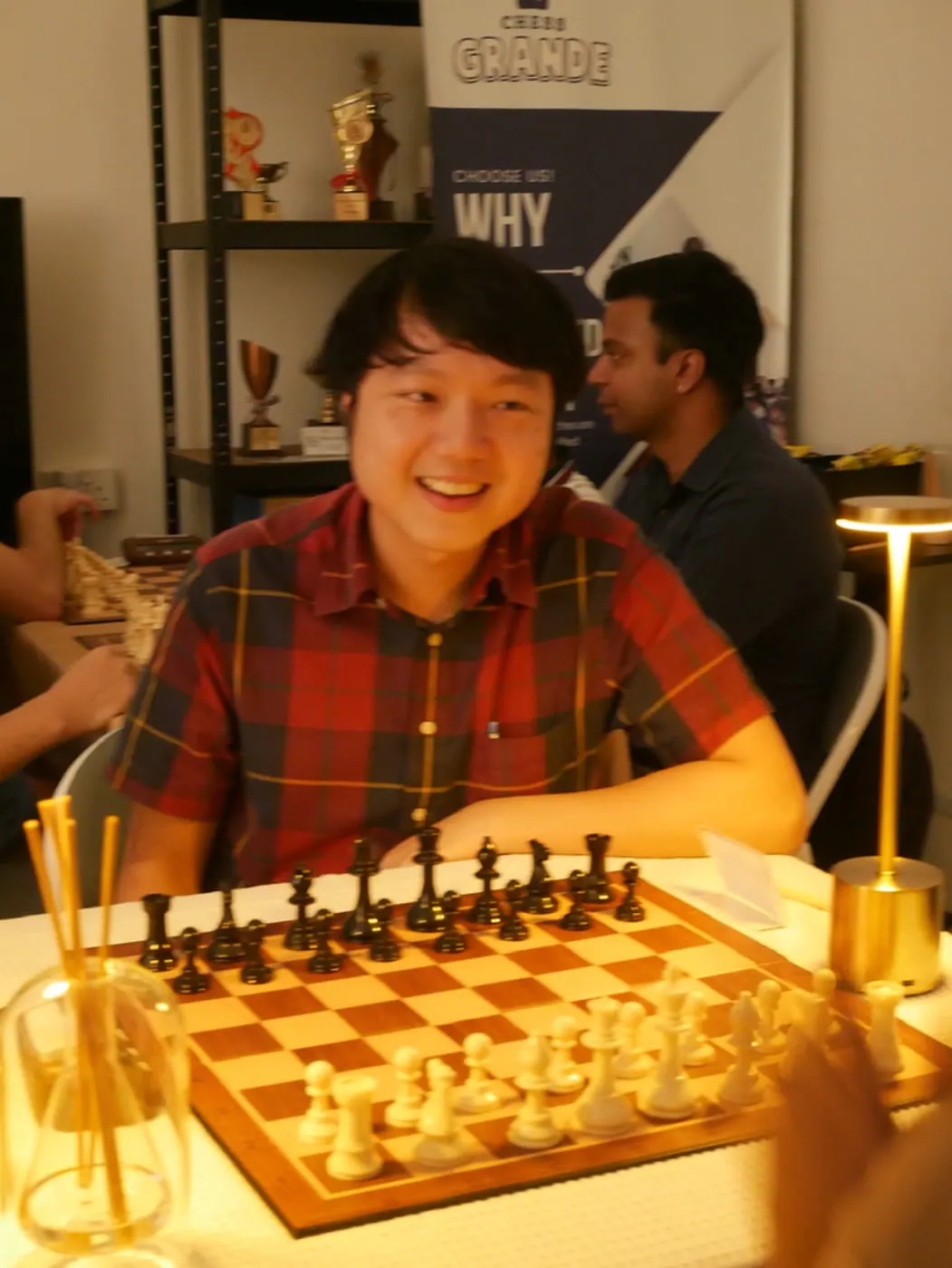 A smiling participant seated at a Checkmate and Chill chessboard