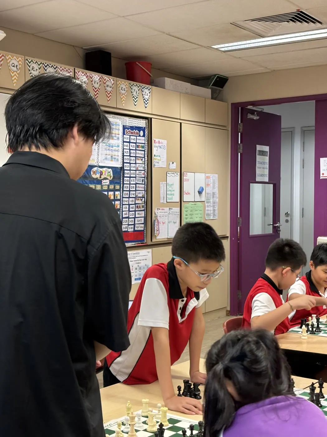 A Chess Grande coach guiding students around their boards at CIS
