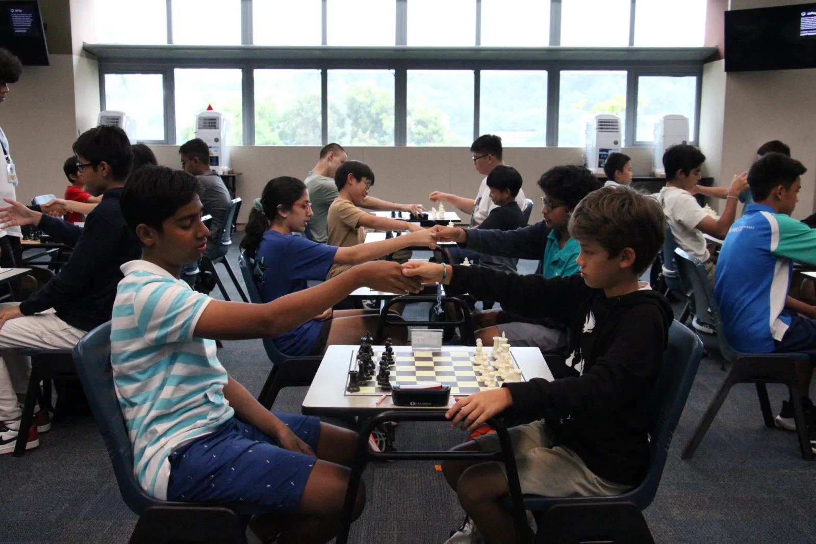 Students playing across long rows of boards at the UWC Chess Challenge