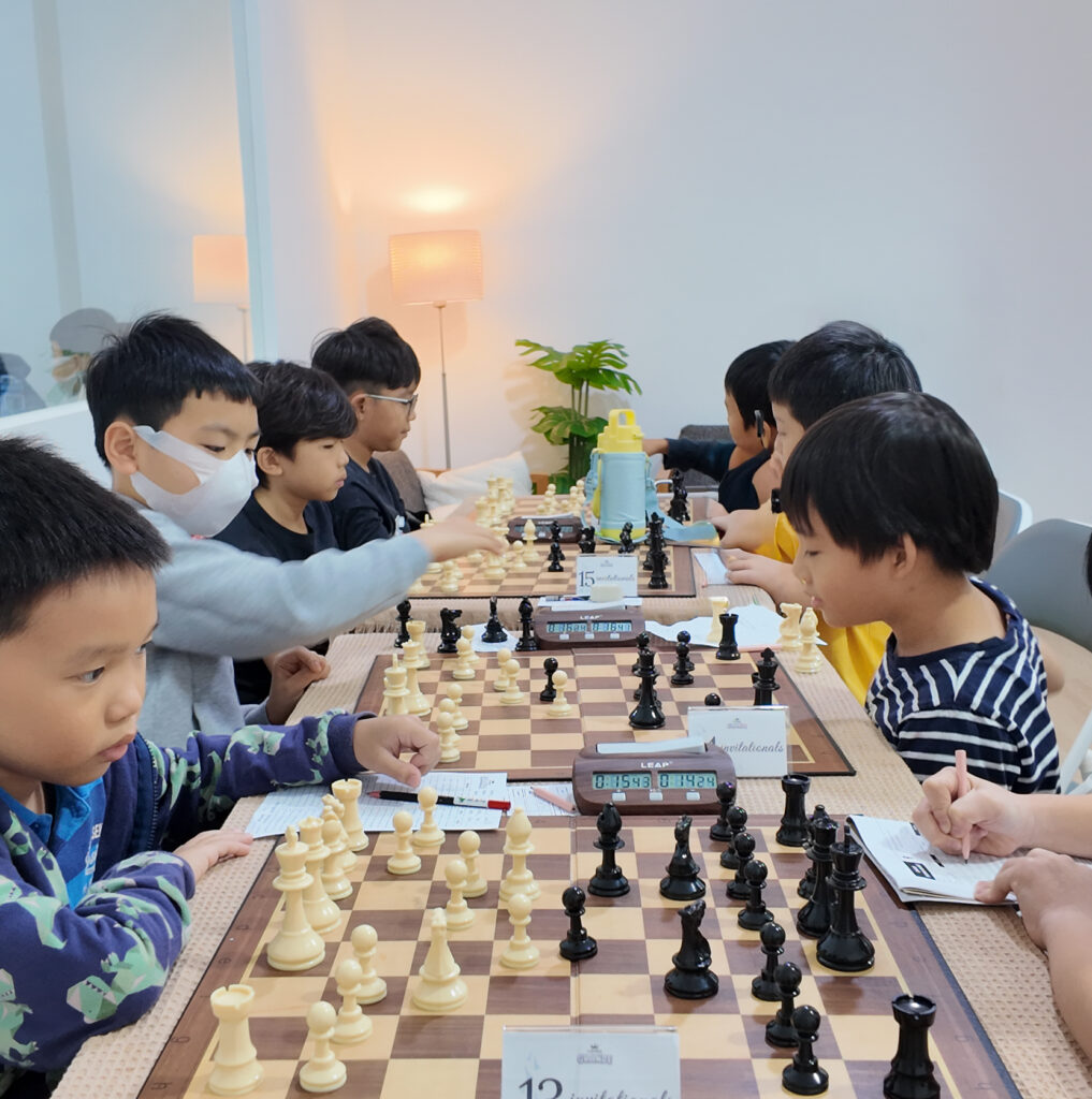 Young Chess Grande players recording moves during a tournament.
