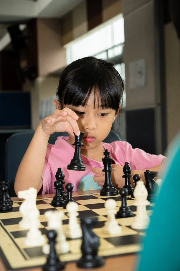A young school tournament player studies the position over the chessboard.