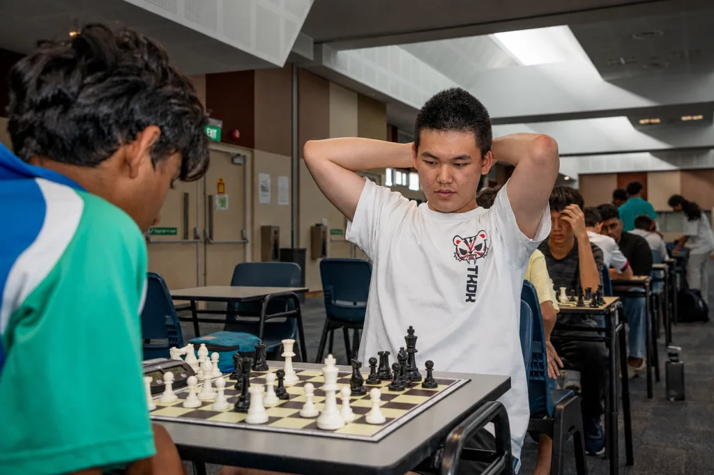 A school tournament player prepares for the next move in a busy playing hall.